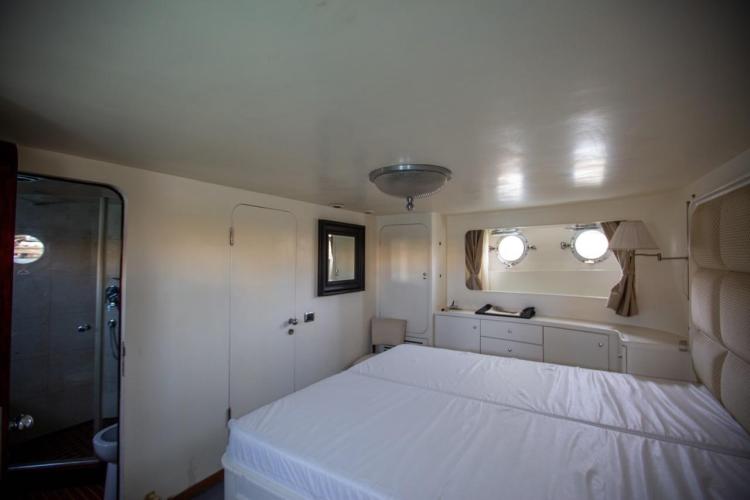 Luxurious cabin interior of 1972 Benetti 33 yacht with porthole windows and elegant decor.